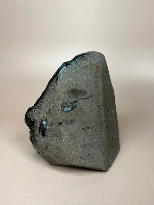 Black druzy chalcedony freeform crystal with shimmering surface on neutral background