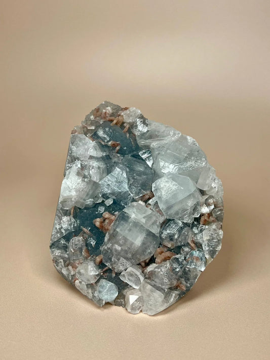 Apophyllite and stilbite crystals on blue chalcedony mineral cluster against neutral background