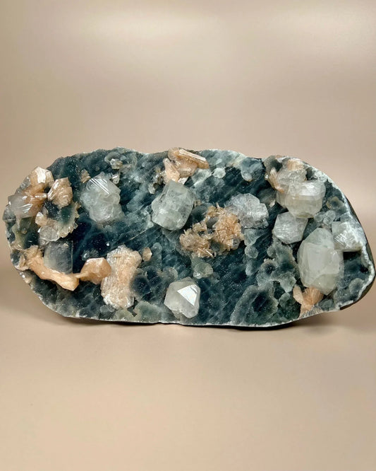 Blue chalcedony slab with apophyllite and stilbite crystal clusters on neutral background