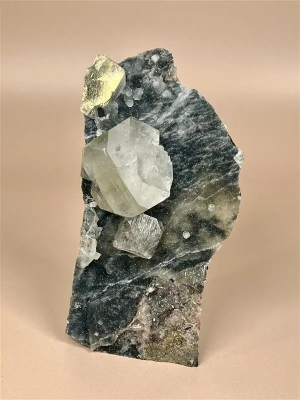 Chunky black chalcedony with apophyllite and stilbite crystals on beige background